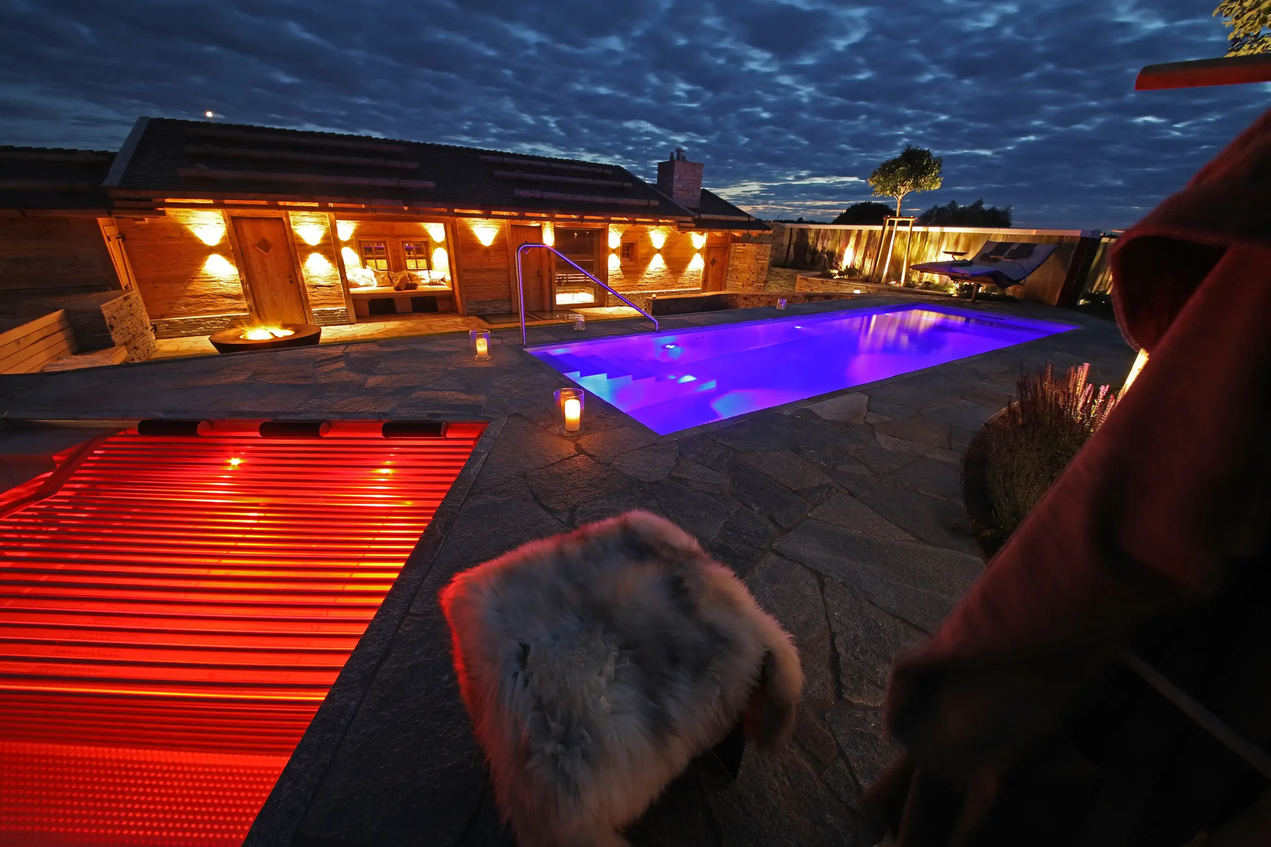 Terrassen Überblick mit Feuerring, Pool und Soundanlage im Dunkeln