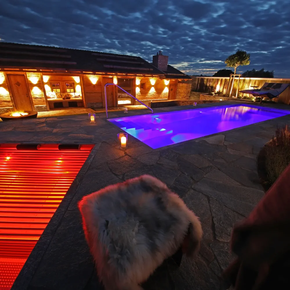 Terrassen Überblick mit Feuerring, Pool und Soundanlage im Dunkeln